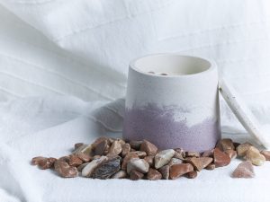 Vela de soja de higuera con piedra rodada roja y envase artesanal de cemento