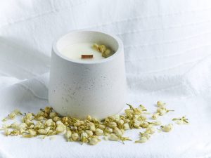 vela artesanal de jazmín en envase de cemento con brotes naturales