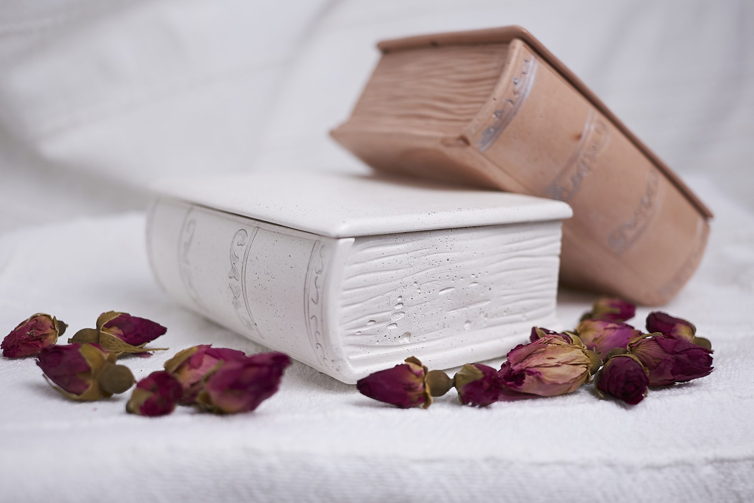 Vela de soja aromática Rosa & Oud 16 Detalle del envase artesanal de cemento con diseño de libro en color blanco y cuero con aroma floral y amaderado