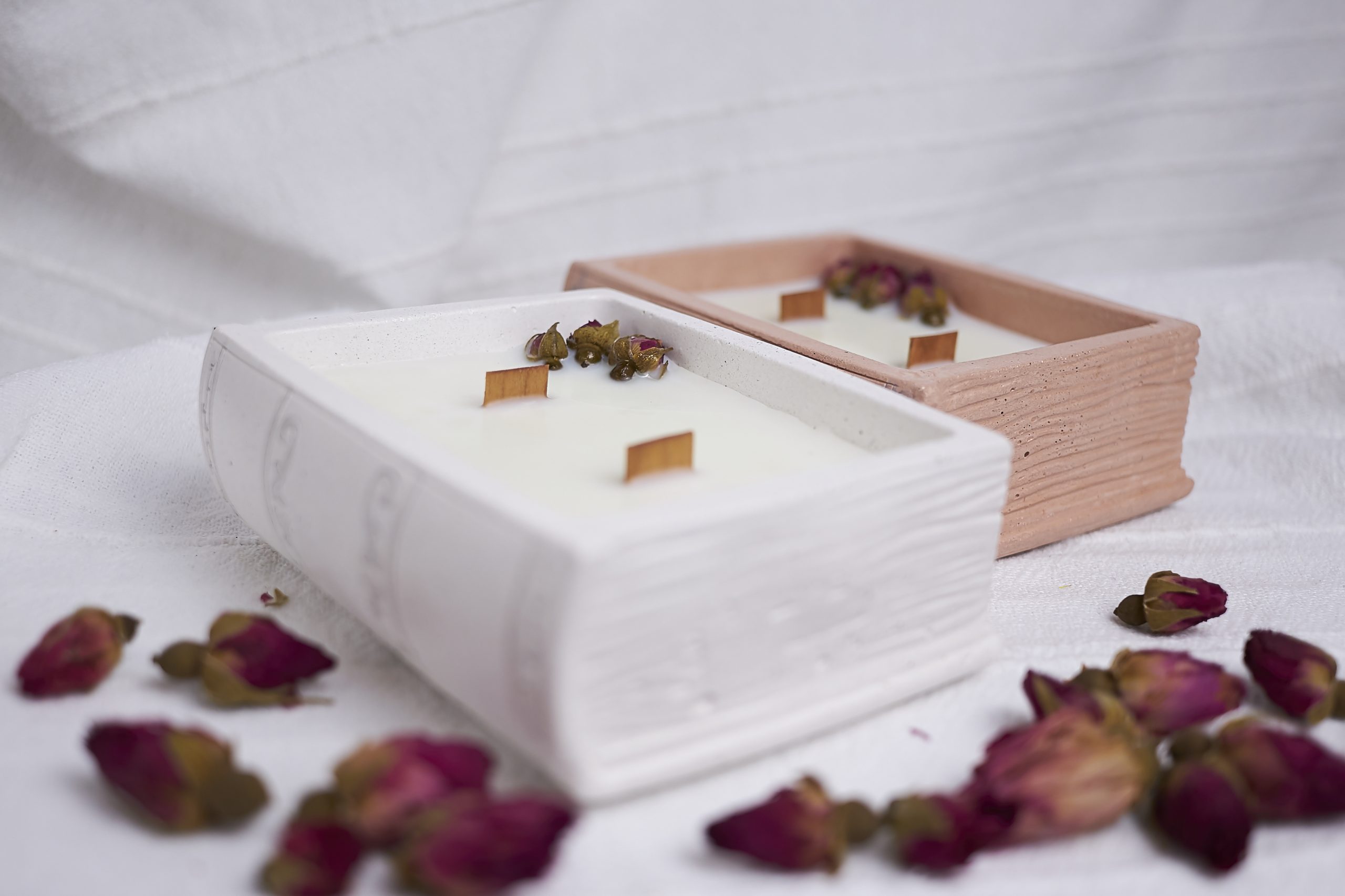 Vela de soja aromática Rosa & Oud 14 Detalle del envase artesanal de cemento con diseño de libro en color blanco y cuero con aroma floral y amaderado